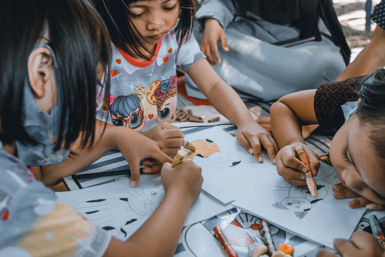 Children drawing with crayons at a preschool table