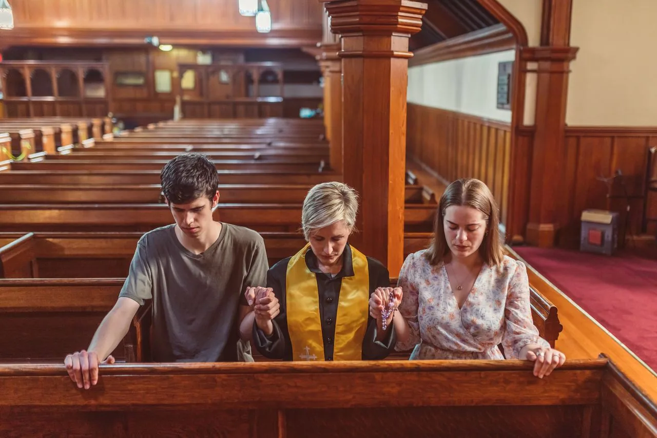 Church members holding hands in prayer in the pews